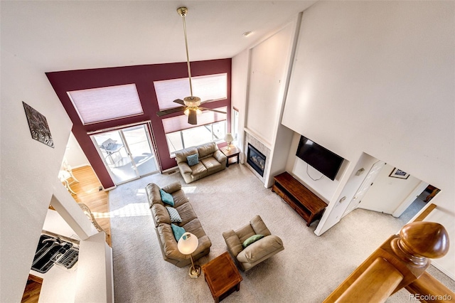 935 Green Gables Cir, Bennett, CO 80102 - carpeted living area featuring a towering ceiling, a glass covered fireplace, and a ceiling fan