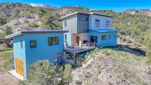 6644 County Road 110, Salida, CO 81201 - back of house featuring stone siding, a deck with mountain view, and stucco siding