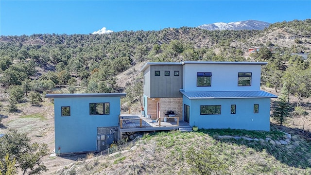 6644 County Road 110, Salida, CO 81201 - back of property with a forest view, a deck with mountain view, a metal roof, and stucco siding