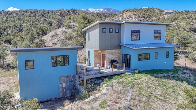 6644 County Road 110, Salida, CO 81201 - back of house with stone siding, a deck with mountain view, a metal roof, stucco siding, and a standing seam roof