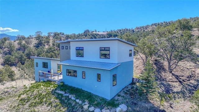 6644 County Road 110, Salida, CO 81201 - view of side of property featuring a standing seam roof, stucco siding, a metal roof, and a forest view