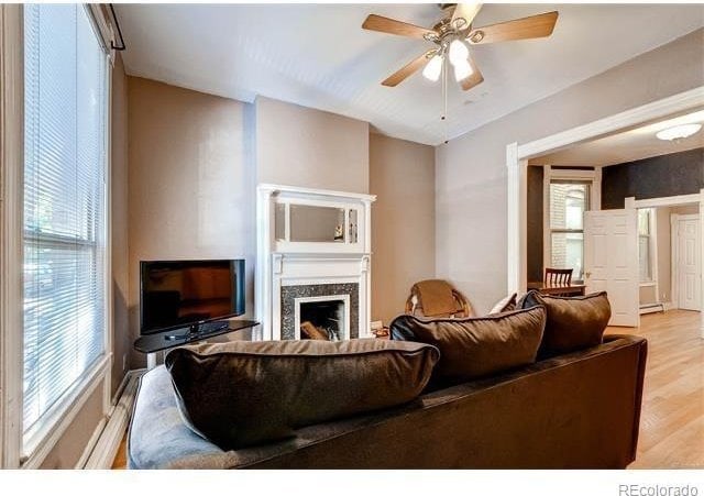 1767 N Washington St, Denver, CO 80203 - living area featuring light wood-style flooring, a fireplace, ceiling fan, and baseboard heating
