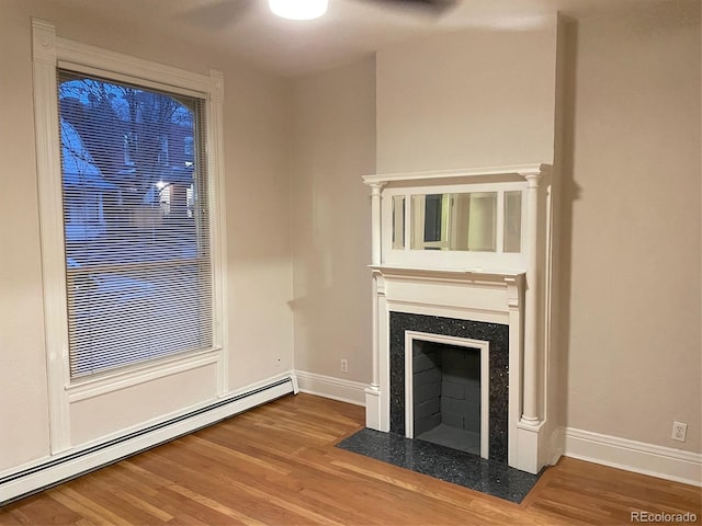 1767 N Washington St, Denver, CO 80203 - unfurnished living room featuring baseboard heating, wood finished floors, baseboards, and a high end fireplace