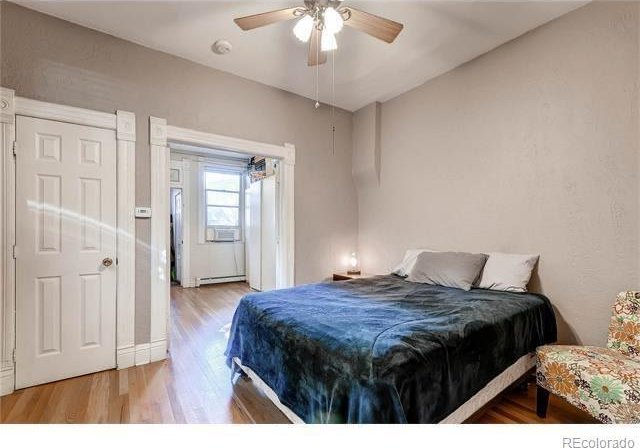 1767 N Washington St, Denver, CO 80203 - bedroom featuring wood finished floors, baseboard heating, cooling unit, and ceiling fan