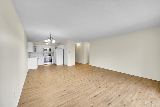 unfurnished living room with a sink, light wood-style flooring, and a chandelier