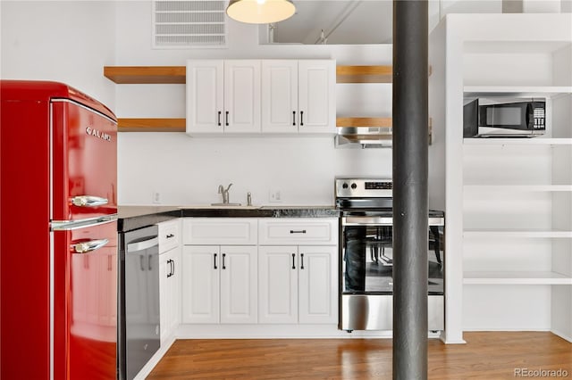 kitchen with appliances with stainless steel finishes, sink, white cabinets, and light hardwood / wood-style flooring