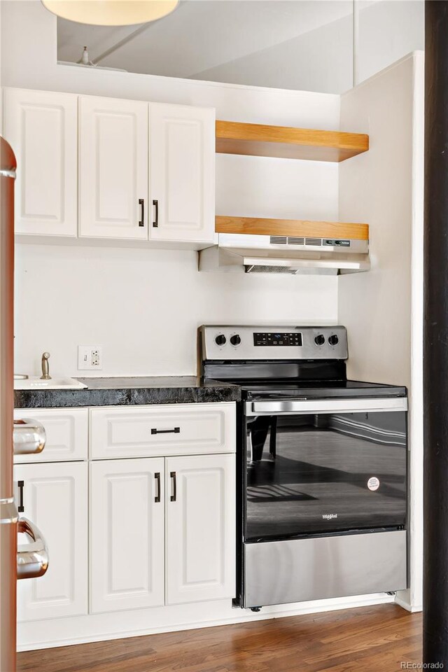 1617 California St Unit 3B, Denver, CO 80202 - kitchen with stainless steel range with electric stovetop, under cabinet range hood, white cabinetry, wood finished floors, and dark countertops