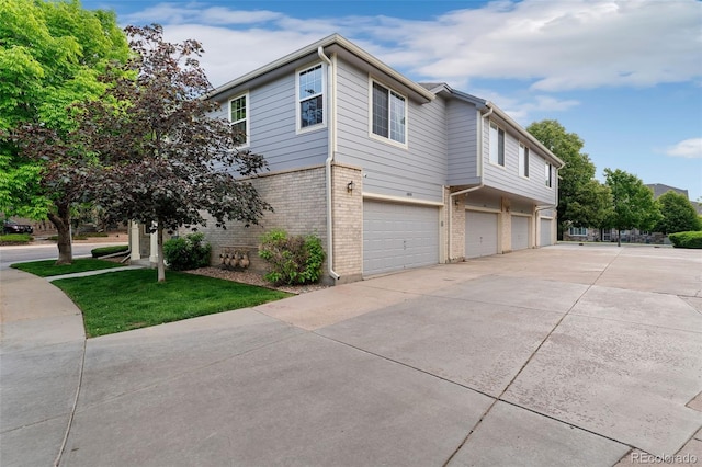 1385 W 112th Ave Unit D, Denver, CO 80234 - view of side of home featuring driveway, brick siding, and an attached garage