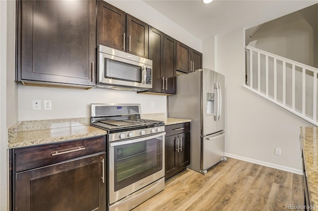 3386 Valentia St, Denver, CO 80238 - kitchen with appliances with stainless steel finishes, light wood-type flooring, dark brown cabinetry, light stone counters, and baseboards