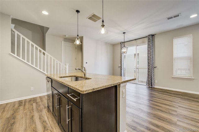 3386 Valentia St, Denver, CO 80238 - kitchen featuring a sink, baseboards, dark brown cabinets, light wood-style floors, and pendant lighting