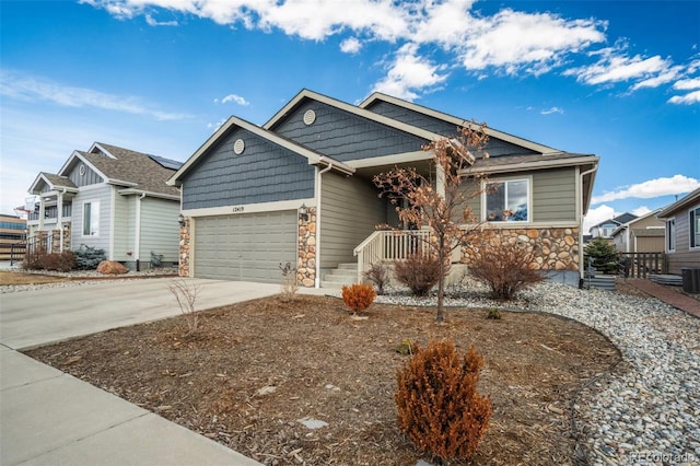 craftsman-style home with driveway, a garage, stone siding, covered porch, and central air condition unit