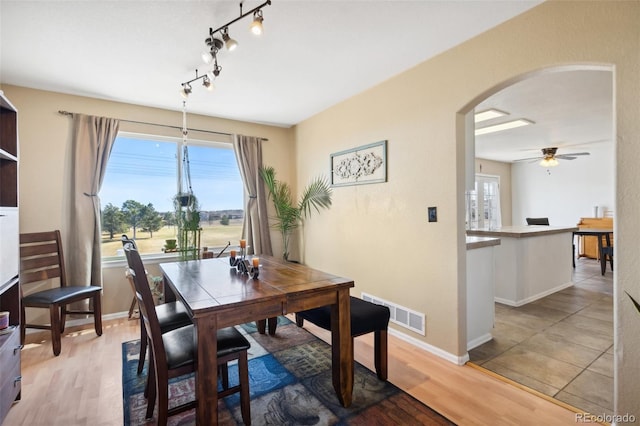 dining room featuring light wood-type flooring, visible vents, arched walkways, and a healthy amount of sunlight