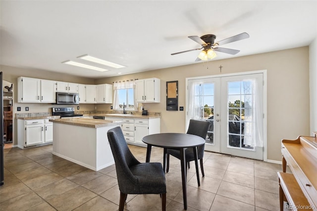 kitchen with a sink, french doors, appliances with stainless steel finishes, white cabinets, and light countertops