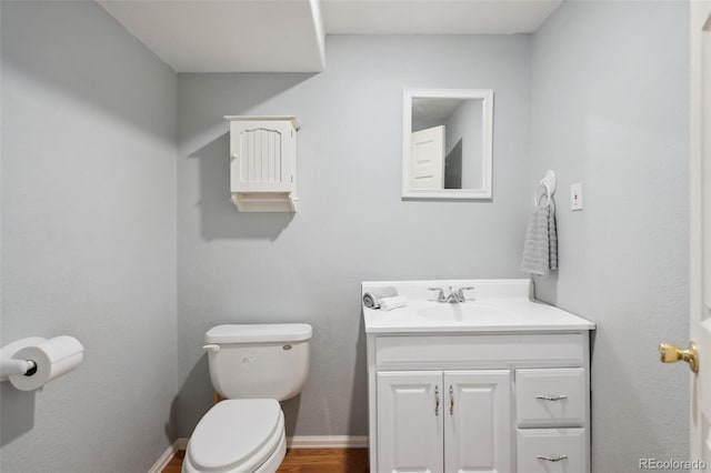 bathroom with vanity, toilet, wood finished floors, and baseboards