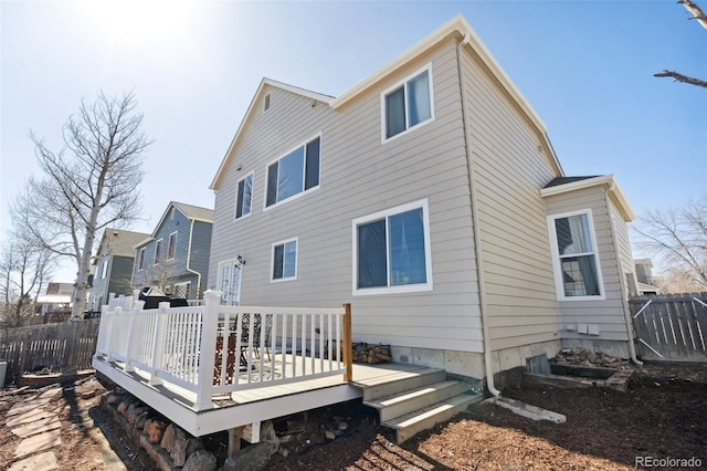 rear view of house with a deck and fence