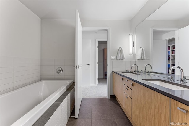 full bathroom featuring a sink, a bath, double vanity, and tile patterned flooring
