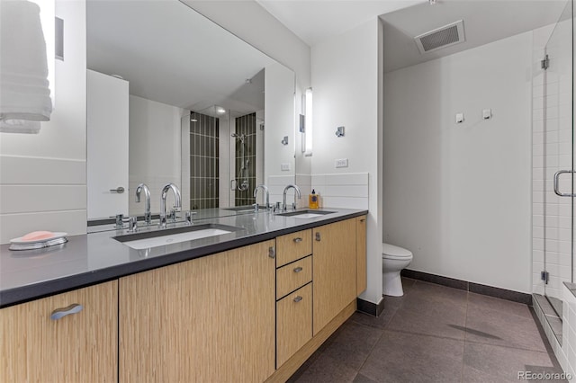 full bath featuring double vanity, tile patterned floors, a shower stall, visible vents, and a sink