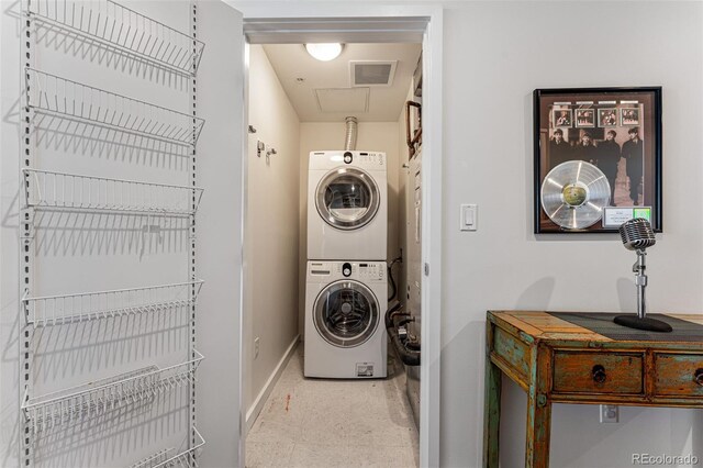 clothes washing area featuring visible vents, laundry area, baseboards, and stacked washer and clothes dryer