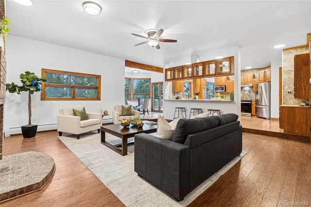 living room featuring light hardwood / wood-style flooring, ceiling fan, and baseboard heating