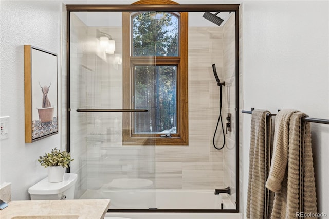 full bathroom with enclosed tub / shower combo, vanity, and toilet