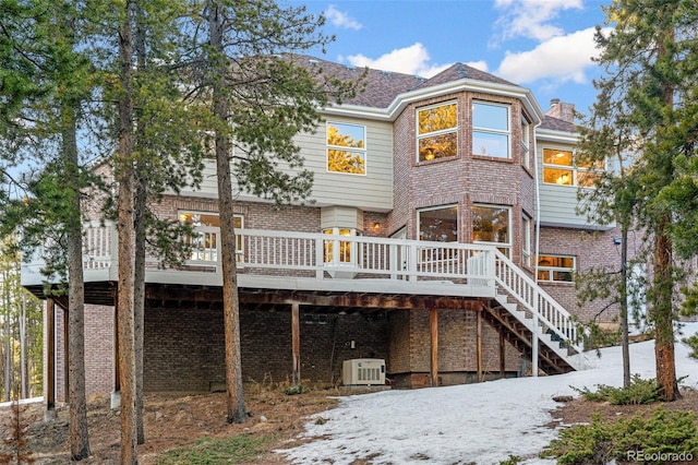 snow covered back of property featuring a wooden deck