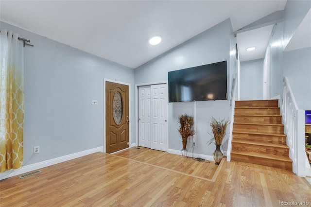 unfurnished living room with baseboards, visible vents, wood finished floors, stairs, and vaulted ceiling