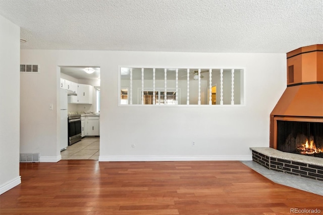 unfurnished living room with a fireplace, light wood-type flooring, and a textured ceiling