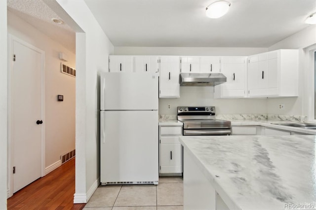 kitchen with stainless steel electric range oven, white cabinets, and white fridge