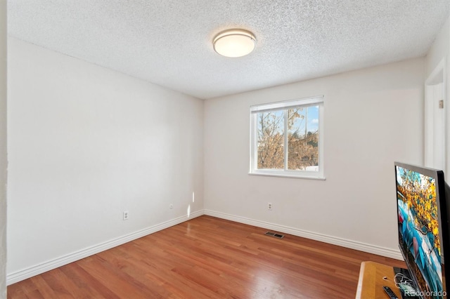 spare room featuring hardwood / wood-style floors and a textured ceiling