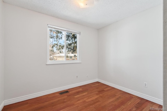 unfurnished room with hardwood / wood-style flooring and a textured ceiling