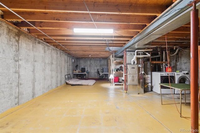 basement with washing machine and clothes dryer, gas water heater, and heating unit