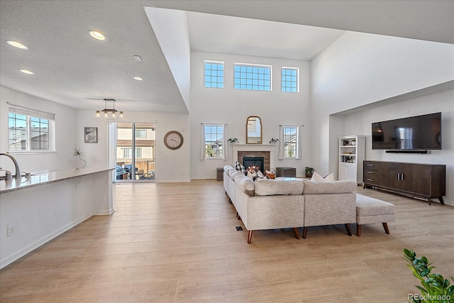 living room with a chandelier, a wealth of natural light, light hardwood / wood-style flooring, and a textured ceiling