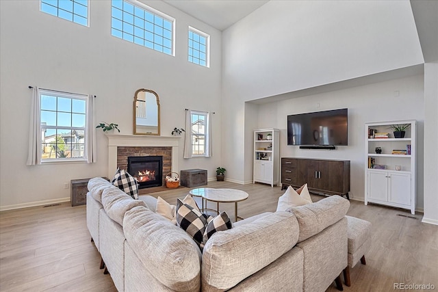 living room featuring a fireplace, light wood-type flooring, and a high ceiling