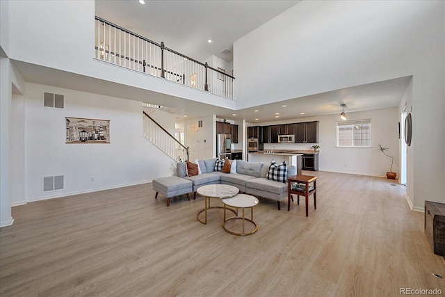 living room featuring a towering ceiling and light hardwood / wood-style floors