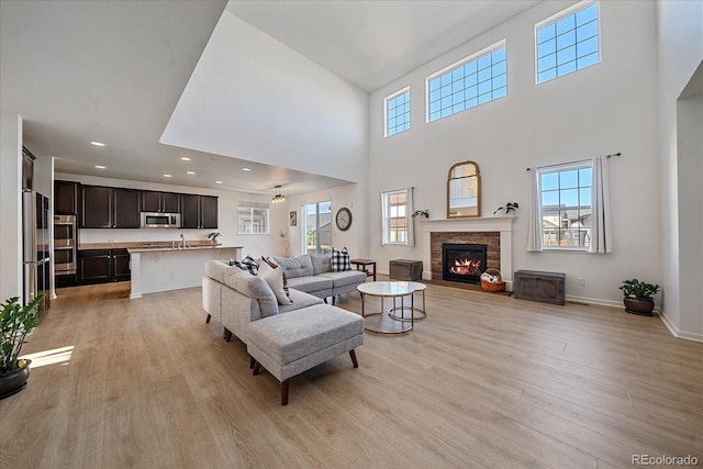 living room with a high ceiling, light hardwood / wood-style flooring, and sink