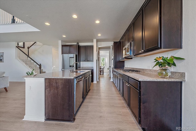 kitchen with dark brown cabinetry, appliances with stainless steel finishes, and a kitchen island with sink