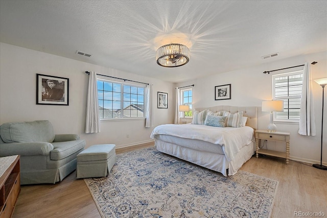 bedroom with a textured ceiling and light hardwood / wood-style flooring