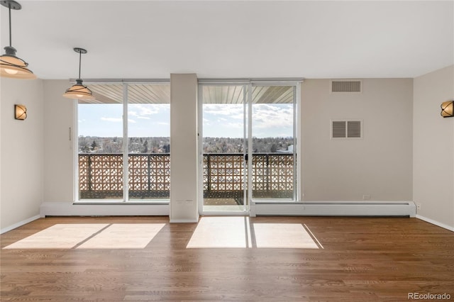 spare room with wood-type flooring, plenty of natural light, and a baseboard radiator