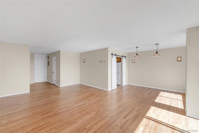 unfurnished room with light hardwood / wood-style flooring and a barn door