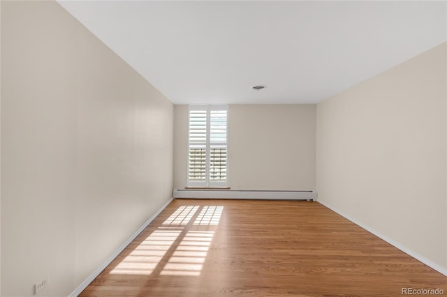 empty room with baseboard heating and light hardwood / wood-style flooring