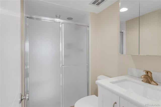 bathroom featuring vanity, an enclosed shower, and toilet