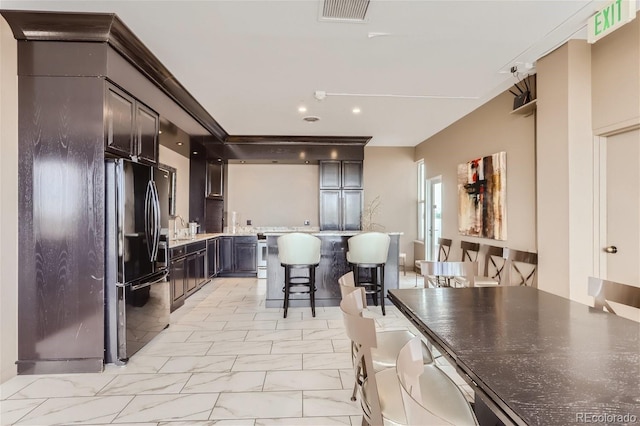 kitchen featuring dark brown cabinetry, a kitchen bar, sink, and black refrigerator with ice dispenser