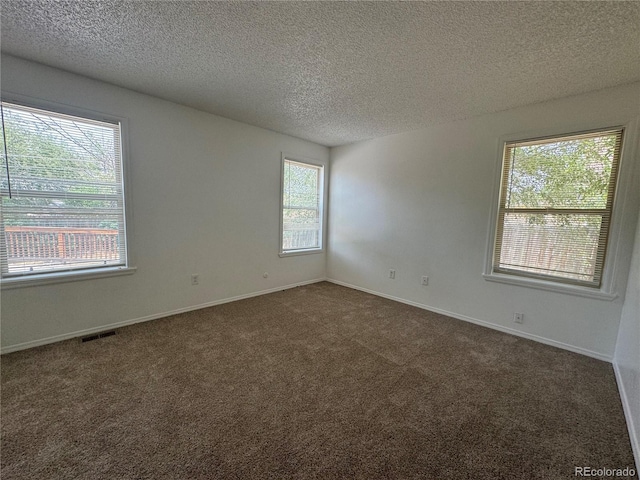 empty room featuring a textured ceiling and dark colored carpet