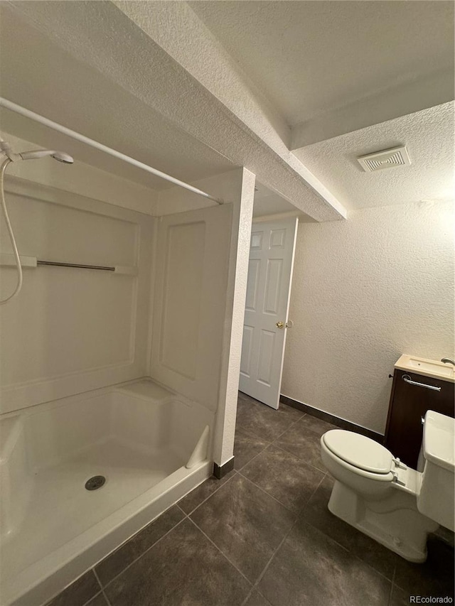 bathroom featuring a shower, tile patterned floors, a textured ceiling, and toilet