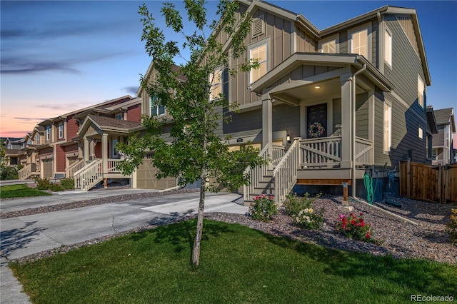 view of front of house with an attached garage, fence, concrete driveway, board and batten siding, and a yard