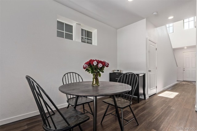 dining room with wood finished floors, baseboards, a towering ceiling, and recessed lighting