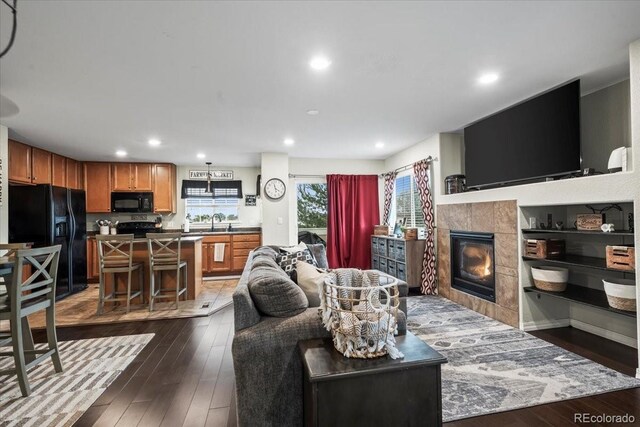 15800 E 121st Ave Unit 4K, Brighton, CO 80603 - living area with dark wood-style floors, a tile fireplace, and recessed lighting