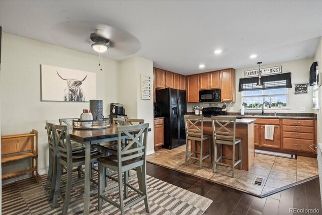 15800 E 121st Ave Unit 4K, Brighton, CO 80603 - kitchen featuring black appliances, dark countertops, light wood finished floors, ceiling fan, and a center island