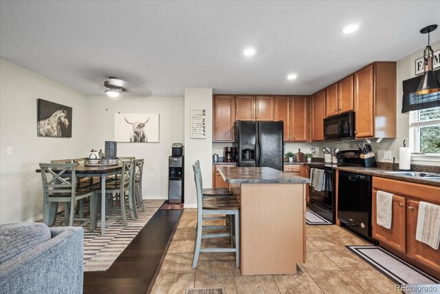 15800 E 121st Ave Unit 4K, Brighton, CO 80603 - kitchen with black appliances, dark countertops, a center island, a breakfast bar area, and baseboards