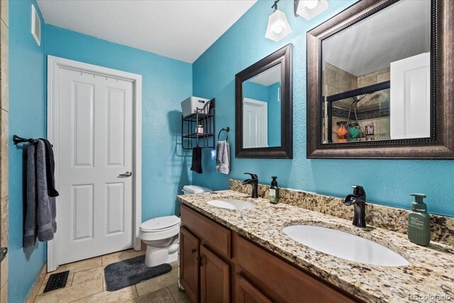 15800 E 121st Ave Unit 4K, Brighton, CO 80603 - bathroom with a stall shower, toilet, double vanity, a textured wall, and stone finish floors